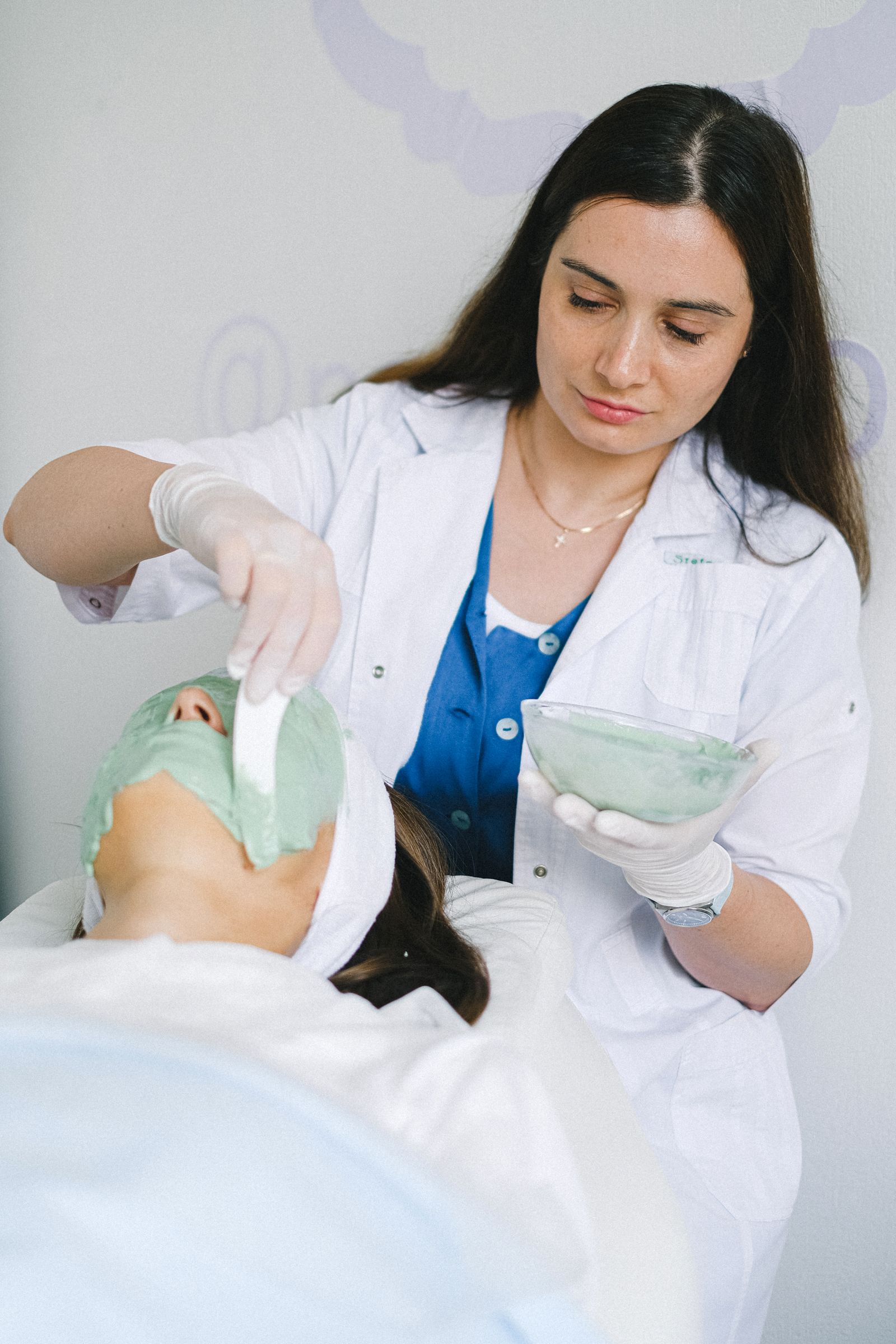 Beauty therapist applying a facial mask to a client